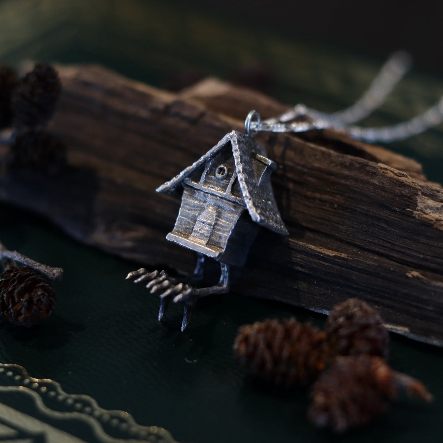 A sterling silver necklace featuring a handcrafted charm of a hut on chicken feet, inspired by Slavic folklore.