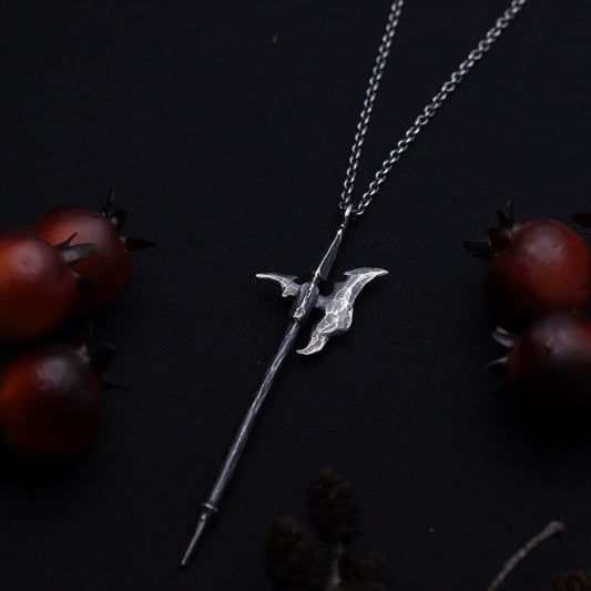 A silver necklace featuring a pendant designed to resemble a fantasy relics axe, displayed with decorative red berries and a dark background.