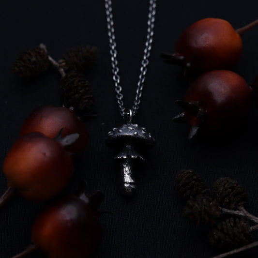 A sterling silver necklace featuring a fly agaric charm displayed against a background