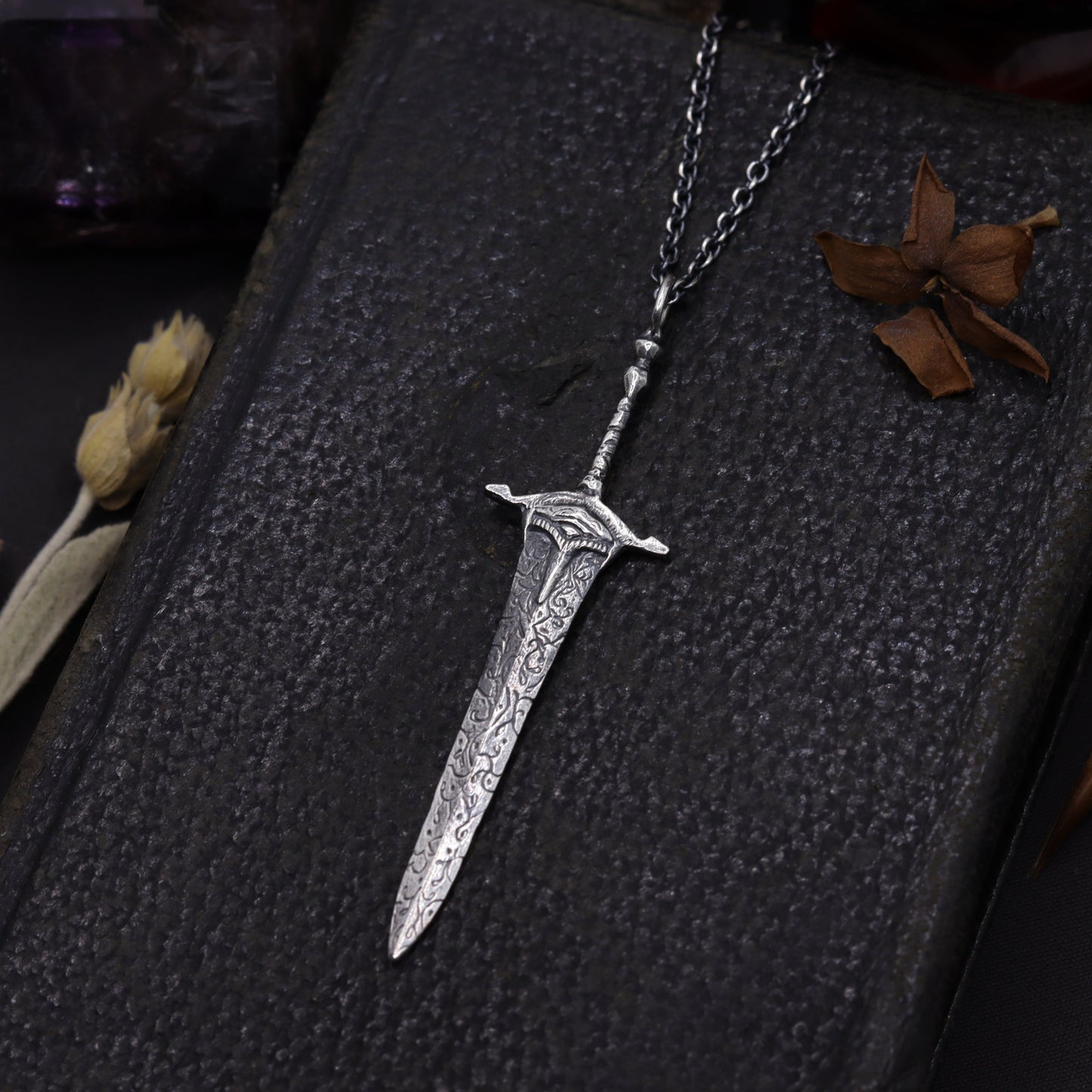 Silver sword-shaped pendant on a dark background