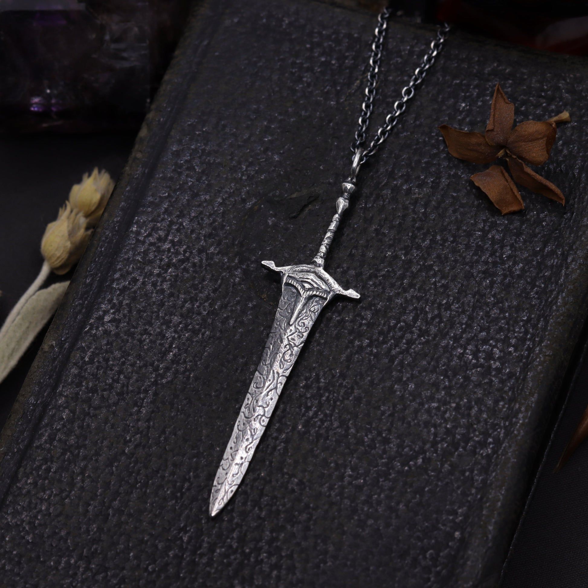 Silver sword-shaped pendant on a dark background