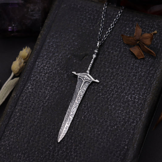 Silver sword-shaped pendant on a dark background