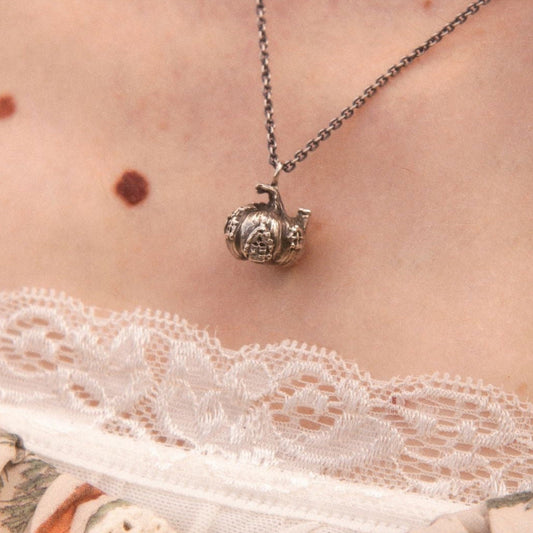 Close-up of a silver pumpkin house charm necklace