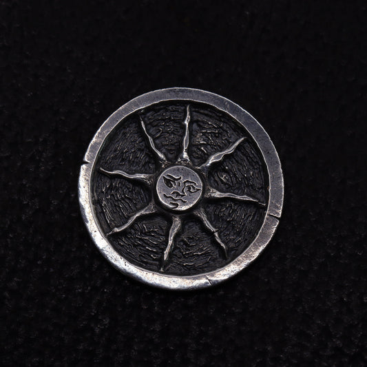 Silver flipping coin with sun design on a textured black background