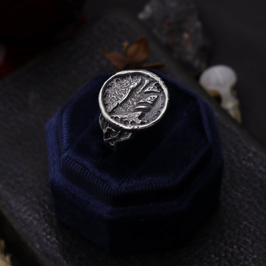 Silver wolf ring design on a blue cushion against a dark background