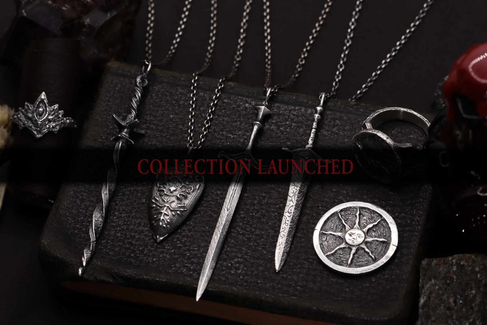 Collection of silver necklaces and rings on a dark surface with 'Collection Launched' text.