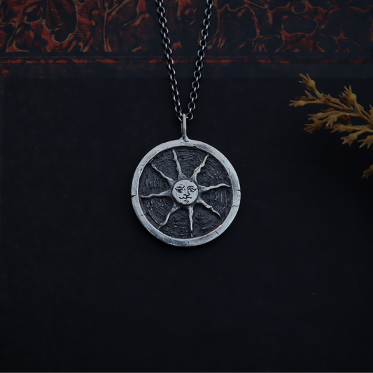 Silver pendant necklace on a dark background with intricate patterns