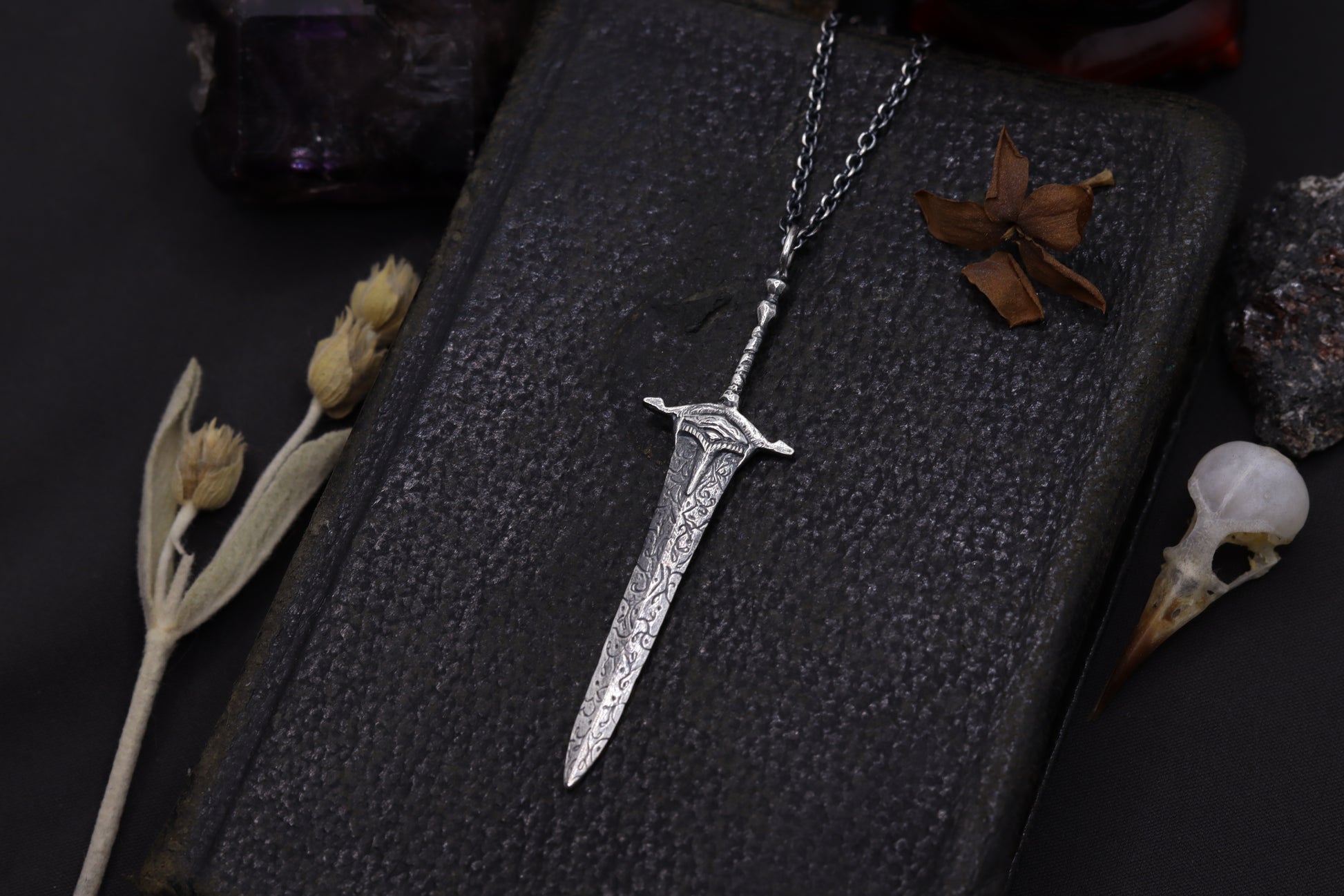 Silver sword-shaped pendant on a dark background