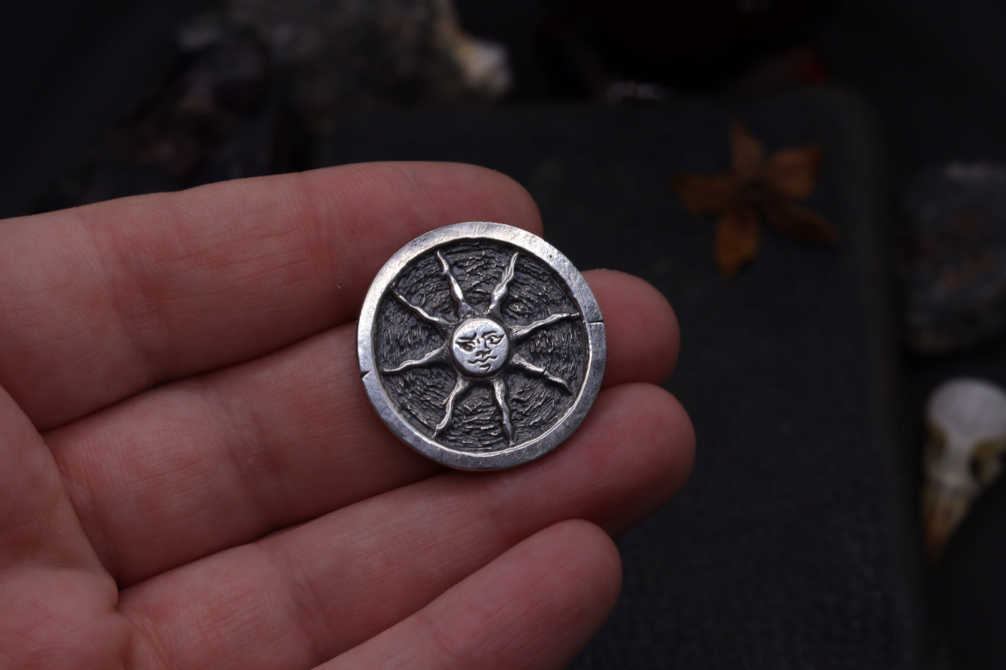 Silver flipping coin with sun design on a textured black background