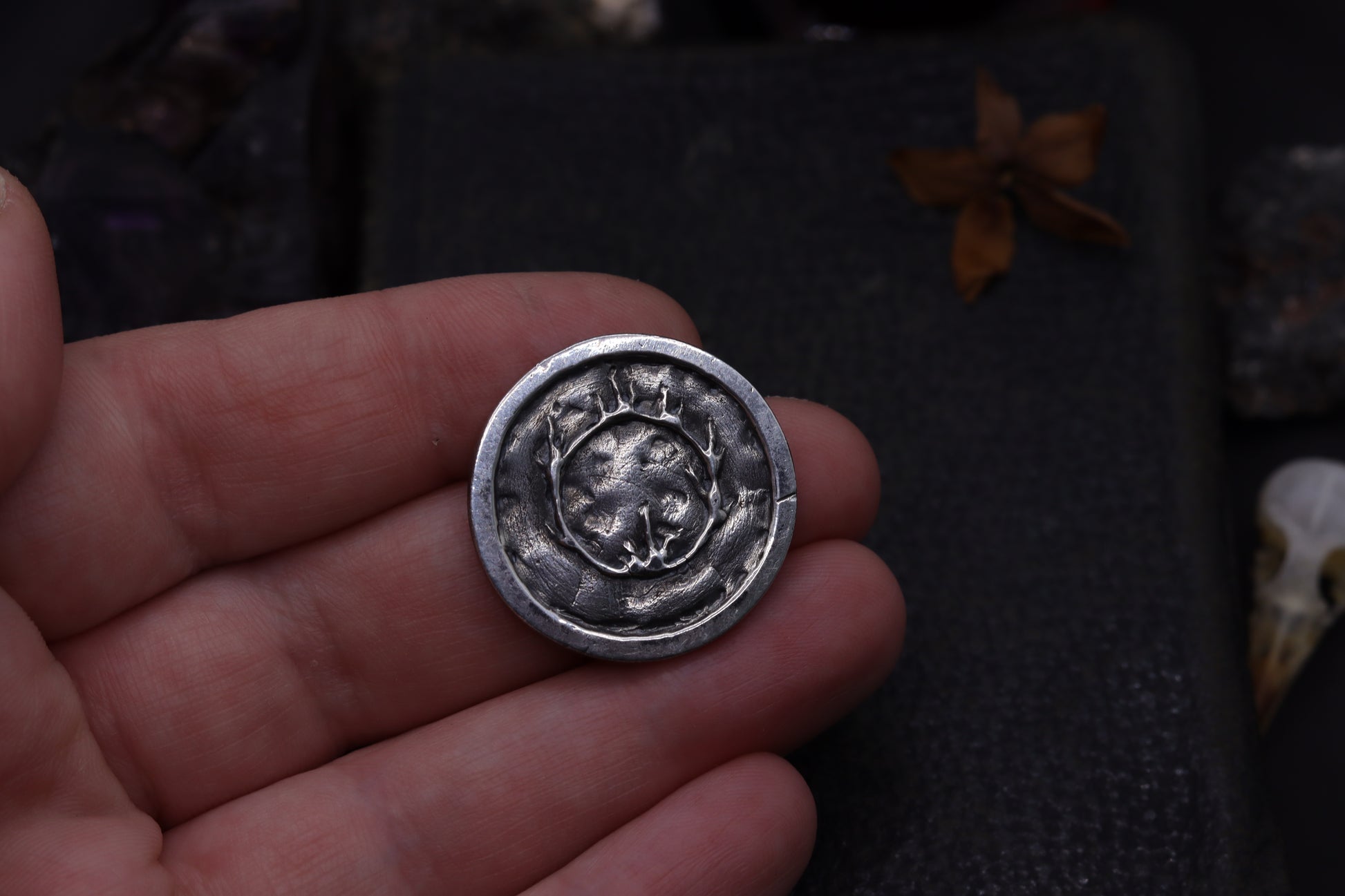 Silver flipping coin with sun design on a textured black background