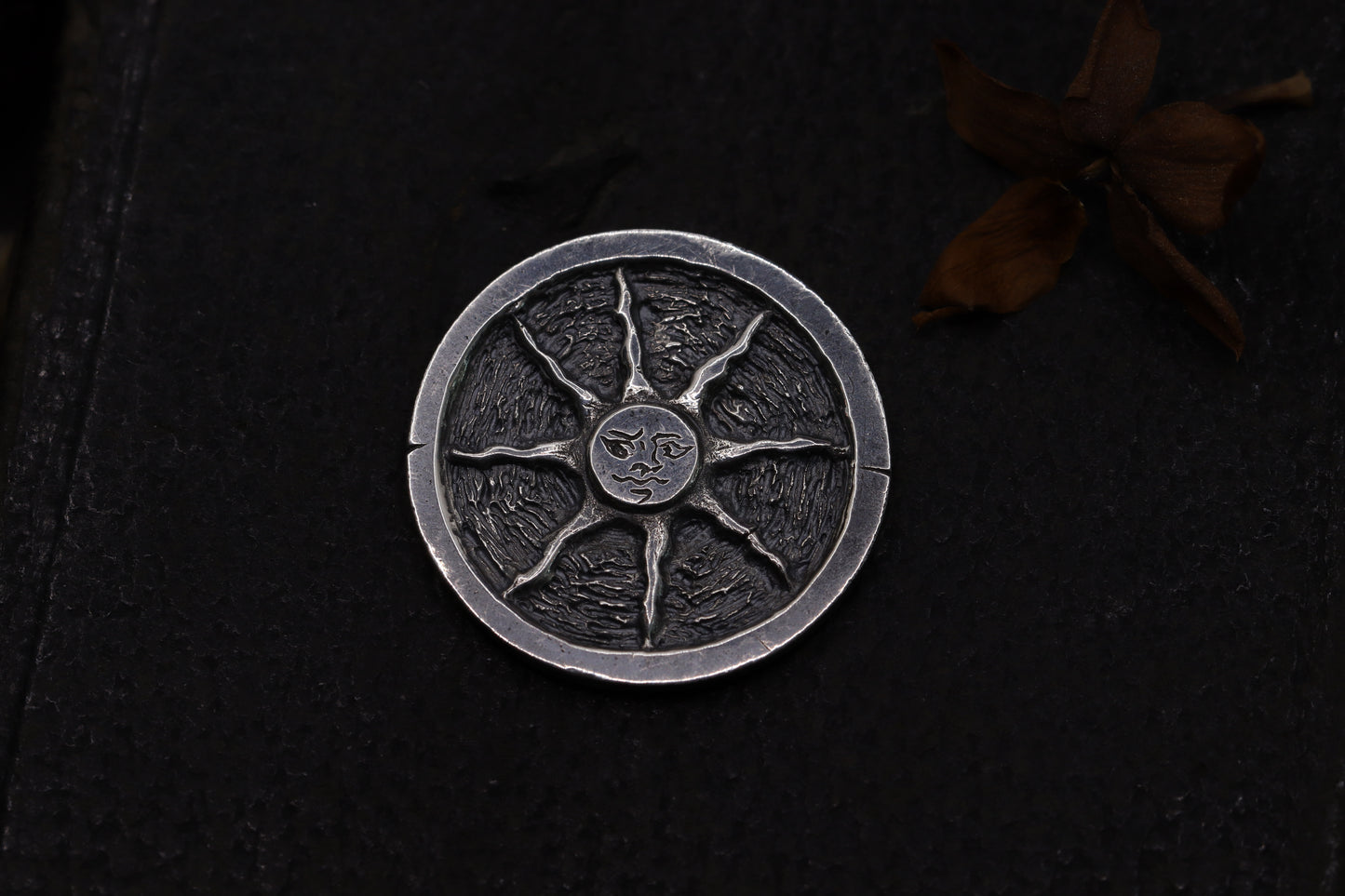 Silver flipping coin with sun design on a textured black background