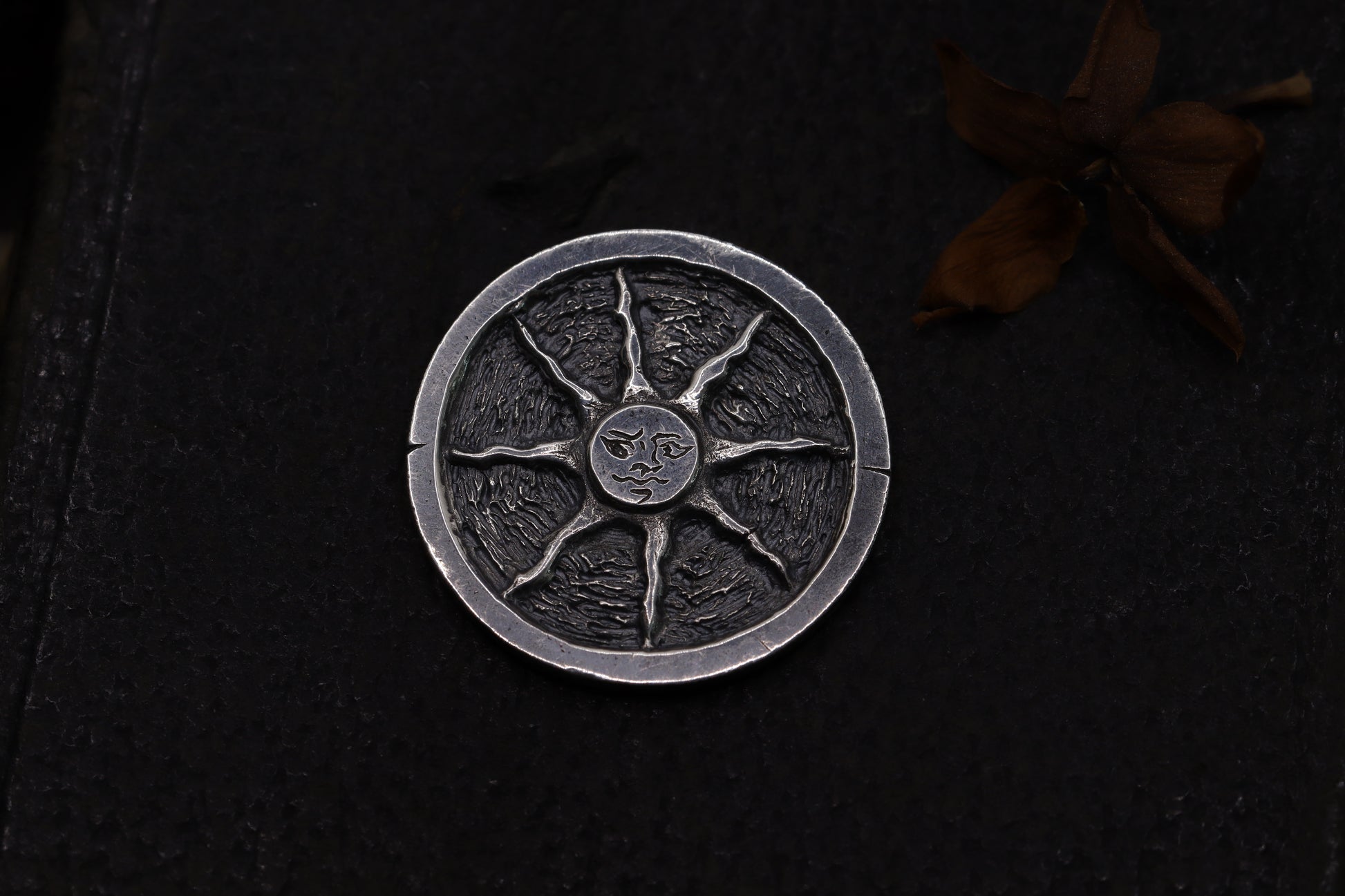Silver flipping coin with sun design on a textured black background