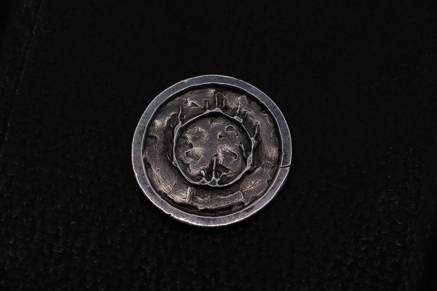 Silver flipping coin with sun design on a textured black background