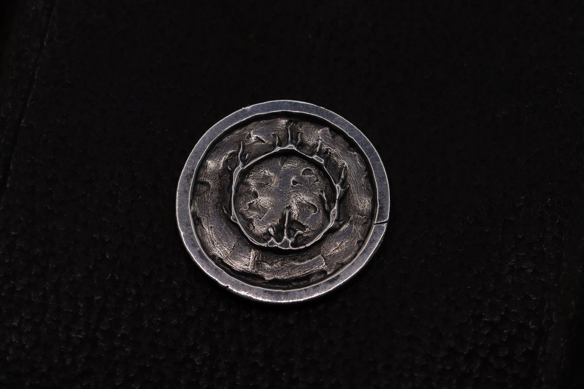 Silver flipping coin with sun design on a textured black background