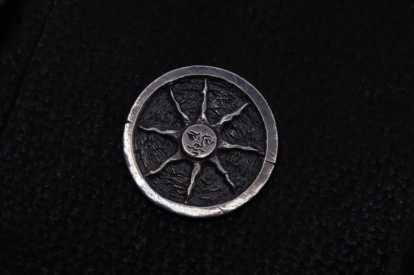 Silver flipping coin with sun design on a textured black background
