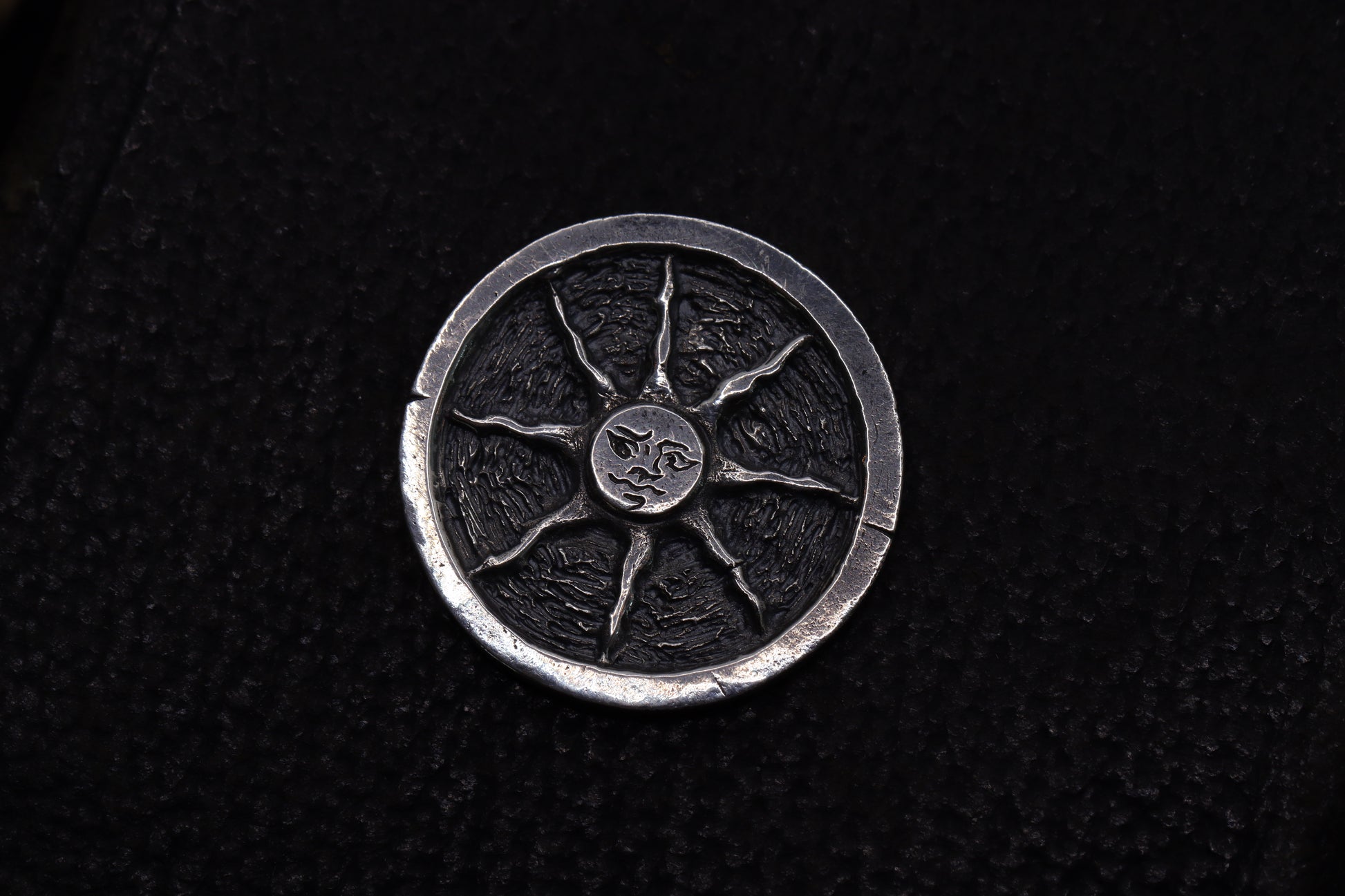 Silver flipping coin with sun design on a textured black background
