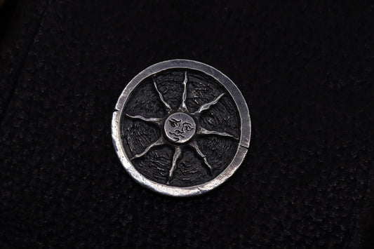 Silver flipping coin with sun design on a textured black background