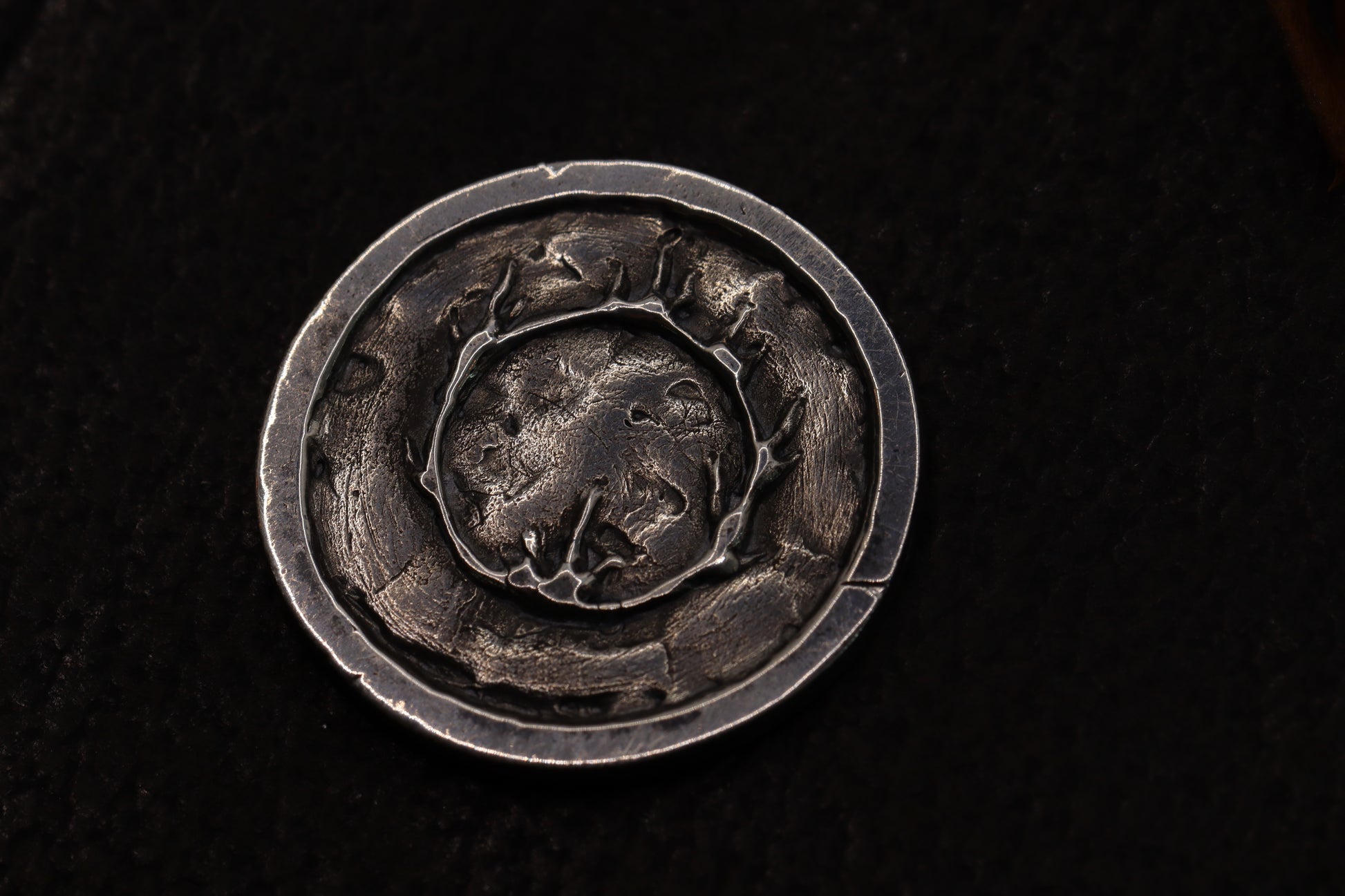 Silver flipping coin with sun design on a textured black background