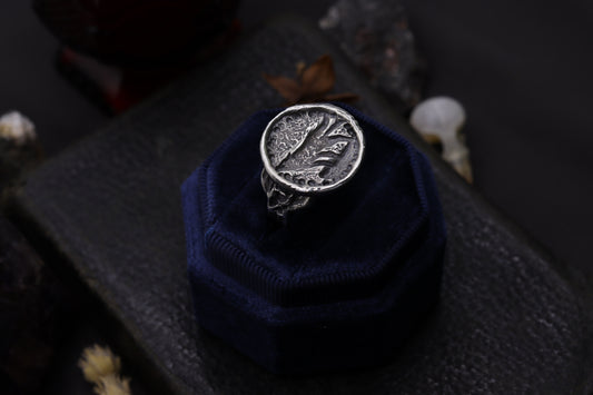 Silver wolf ring design on a blue cushion against a dark background