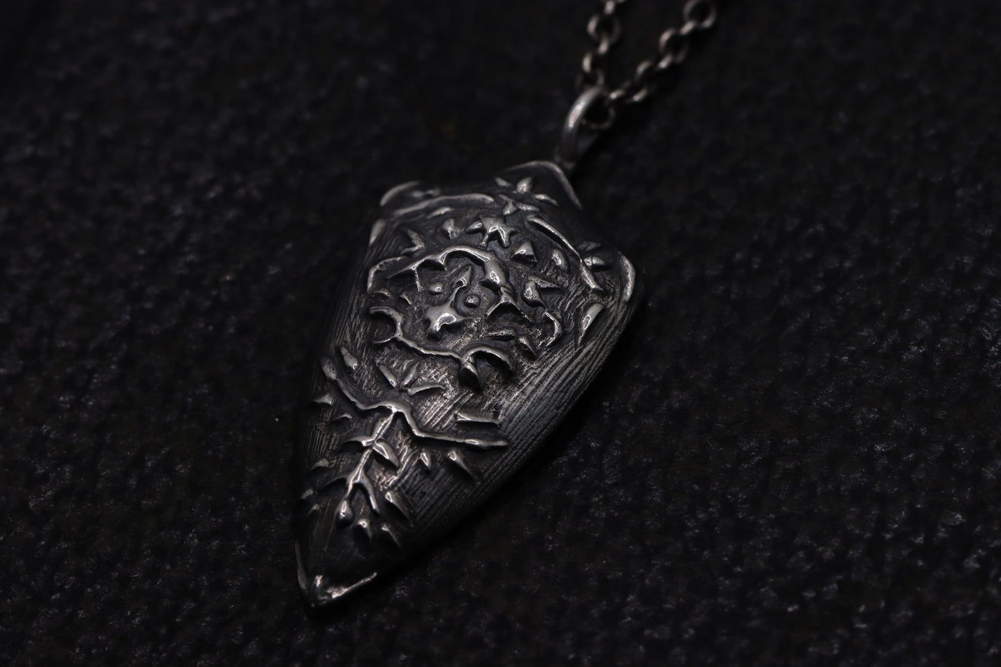 silver shield pendant on a dark textured background