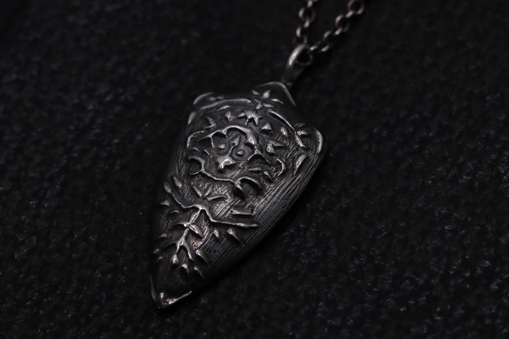 silver shield pendant on a dark textured background