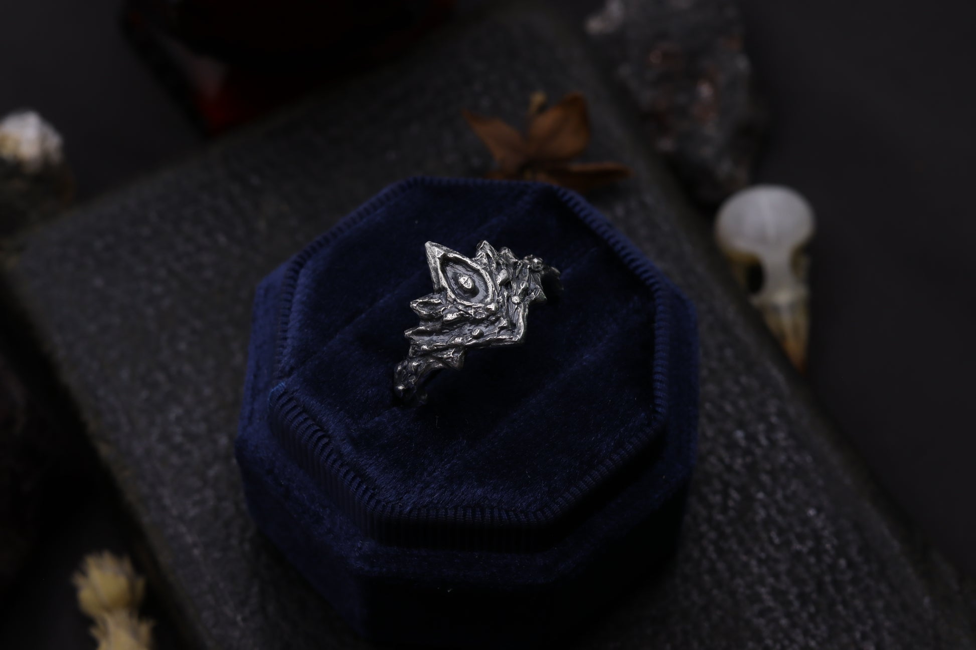 Silver Firekeepers Ring with a unique design on a blue hexagonal stand against a dark background