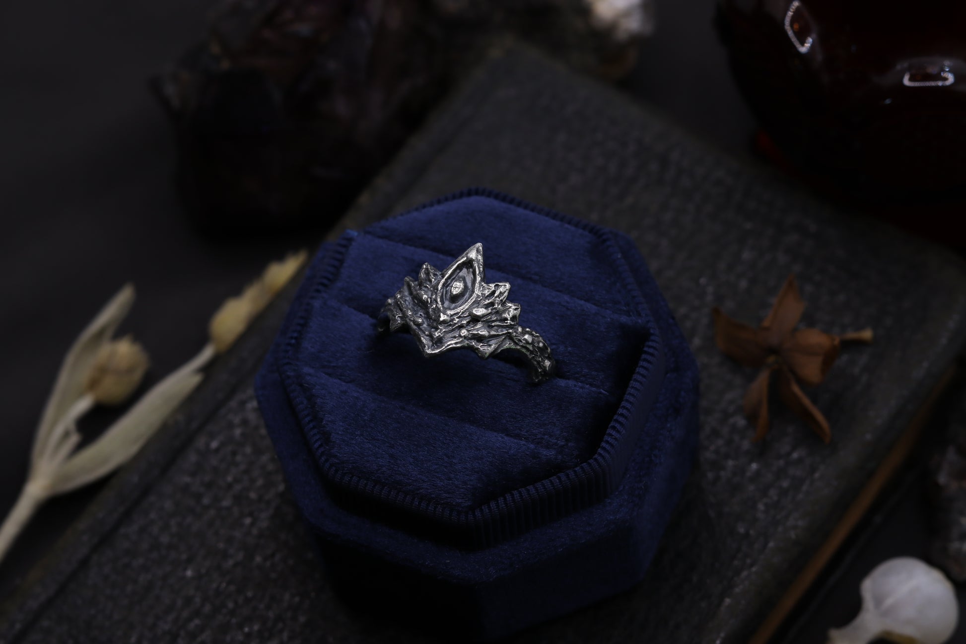 Silver Firekeepers Ring with a blue cushion on a dark textured surface