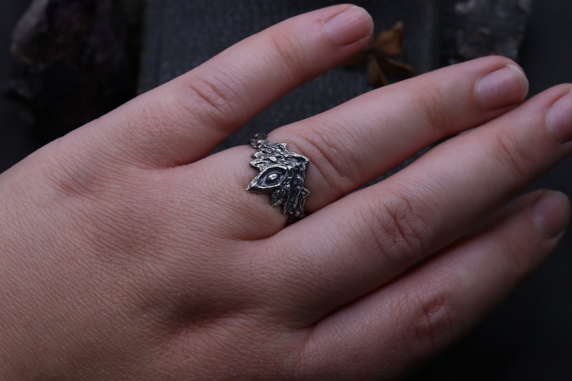Hand wearing a Silver Firekeepers Ring silver ring on a dark background